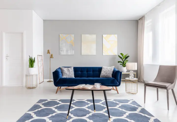 A stylish living room with a deep blue velvet sofa. Learn how to wash velvet to keep it looking luxurious.