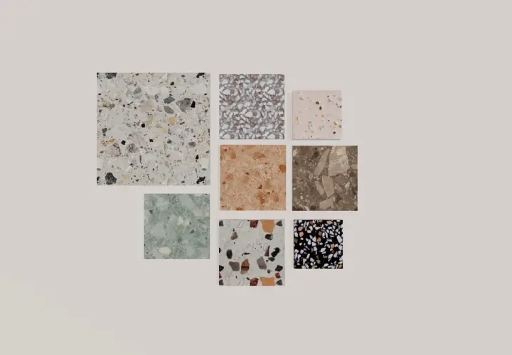 Vari campioni di piastrelle con un affascinante **effetto graniglia** in diverse colorazioni e dimensioni, dal bianco al nero, passando per tonalità naturali e pastello.
