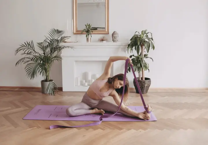 Kobieta ćwiczy iyengar yogę, używając pasa do pogłębiania skłonu.