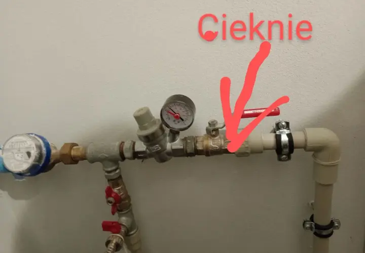 Cieknie zawór antyskażeniowy za wodomierzem. Czerwona strzałka wskazuje miejsce wycieku.