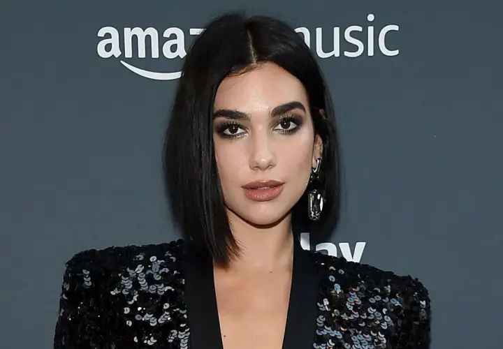 Mujer con un elegante corte pelo bob oscuro, maquillaje dramático y un blazer de lentejuelas.