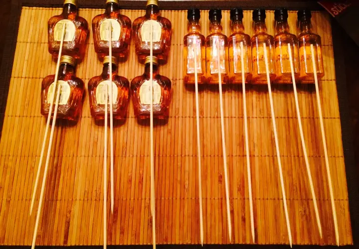 Mini butelki alkoholu z patyczkami na bambusowej macie.