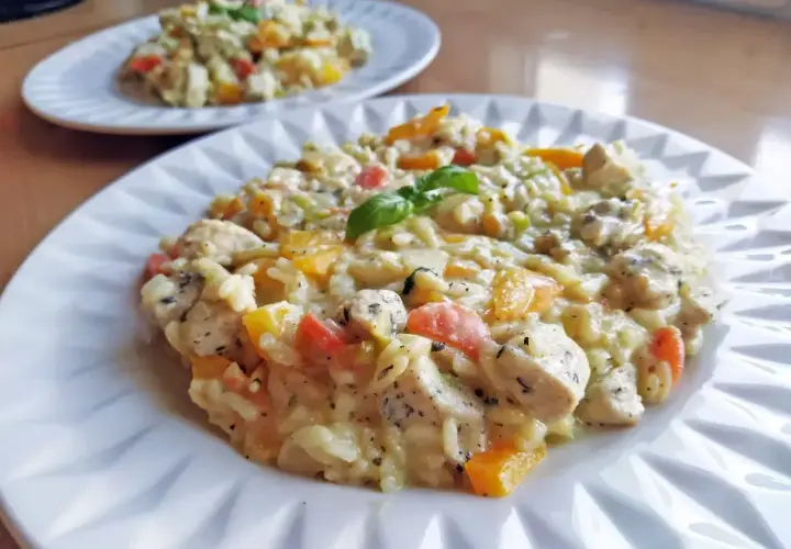 Szybkie risotto z kurczakiem i kolorowymi warzywami, ozdobione listkiem bazylii. Idealne na szybki obiad.