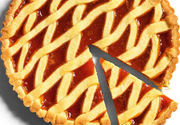 Torta con marmellata, la pasta frolla dorata e croccante è perfetta per la cottura. Due fette sono già state tagliate.