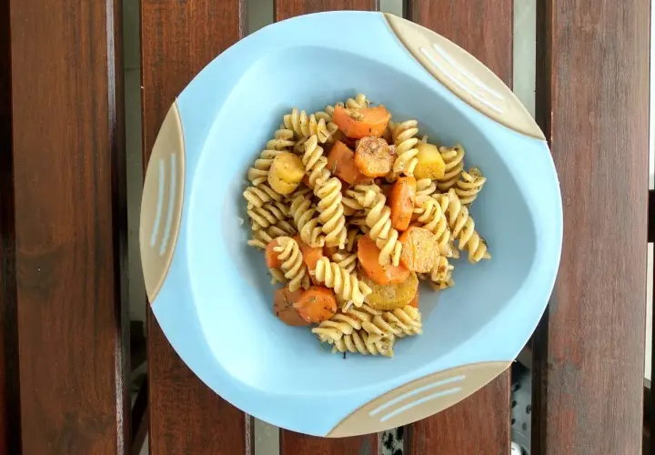 Kolacje dla niemowlaka: makaron fusilli z marchewką i ziemniakami, doprawione ziołami, podane na jasnoniebieskim talerzyku.