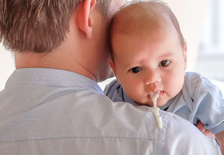 Neonato allattato al seno con reflusso, rigurgita latte sul pigiama del papà.