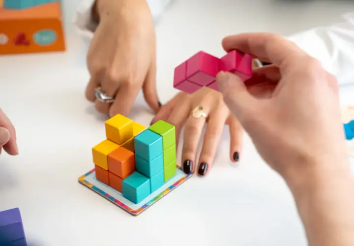 Mani che assemblano blocchi colorati, un gioco che stimola l'alto potenziale cognitivo.