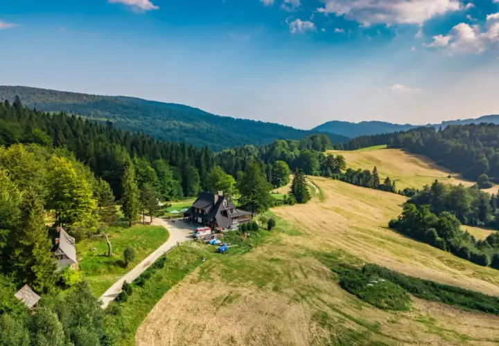 Malownicza bacówka nad Wierchomlą, gdzie trasa turystyczna prowadzi przez zielone wzgórza i lasy.