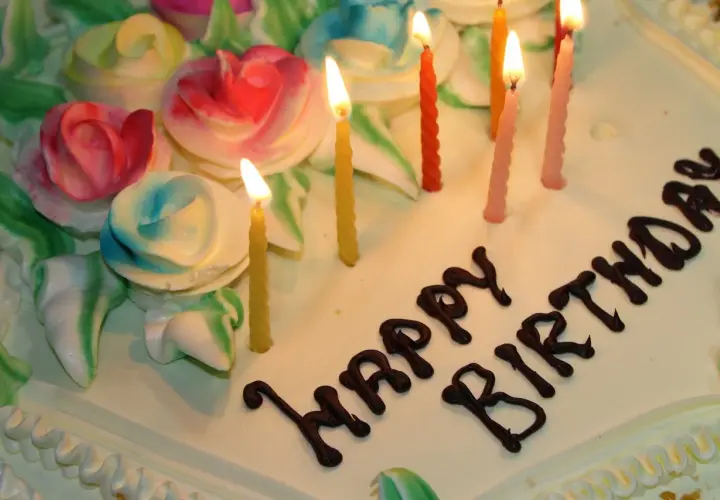 Pastel de cumpleaños con rosas de crema y velas encendidas. ¡Espero que estos textos de cumpleaños para mi novio largas hagan llorar de emoción!