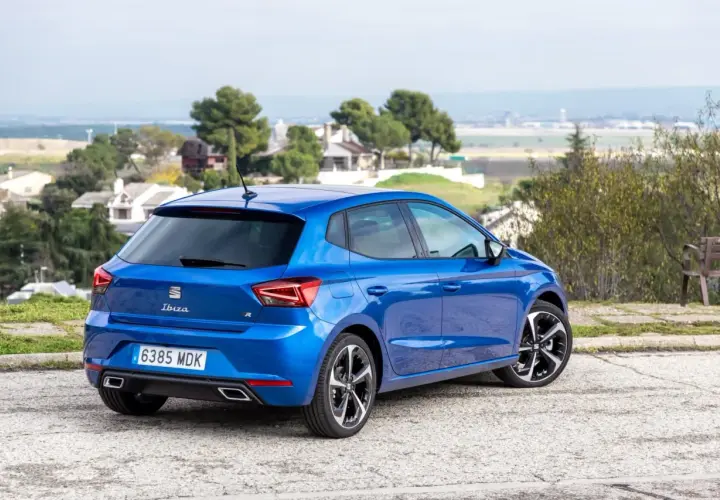Un Seat Ibiza 1.2 gasolina, azul brillante, aparcado en un paisaje con casas y árboles. Opiniones sobre su diseño y rendimiento.