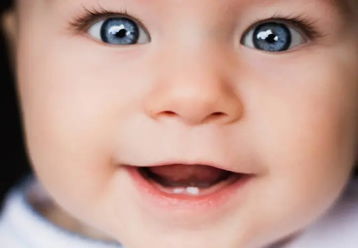 Occhi azzurri e un sorriso che mostra il primo dentino. Una bellissima vista neonati che incanta.