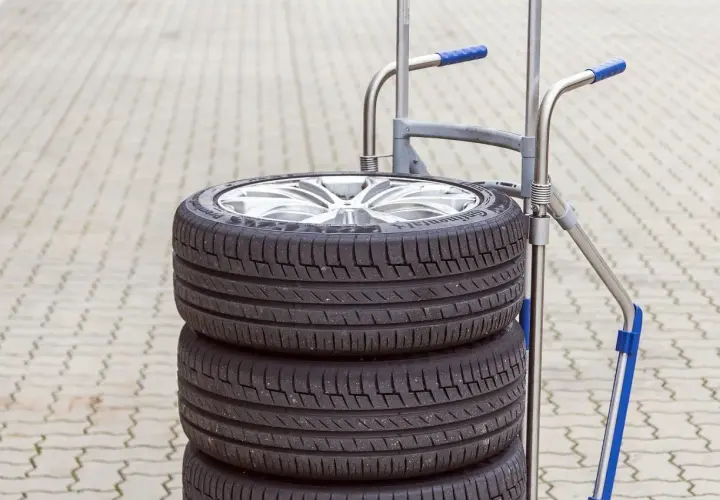 Stos czterech opon na wózku. Zastanawiasz się, ile waży opona? Ten zestaw jest gotowy do transportu.