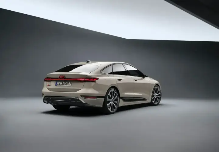 Elegancki tył nowego Audi A6 2025 w kolorze piaskowym, z charakterystycznym pasem świateł LED i sportowymi felgami.