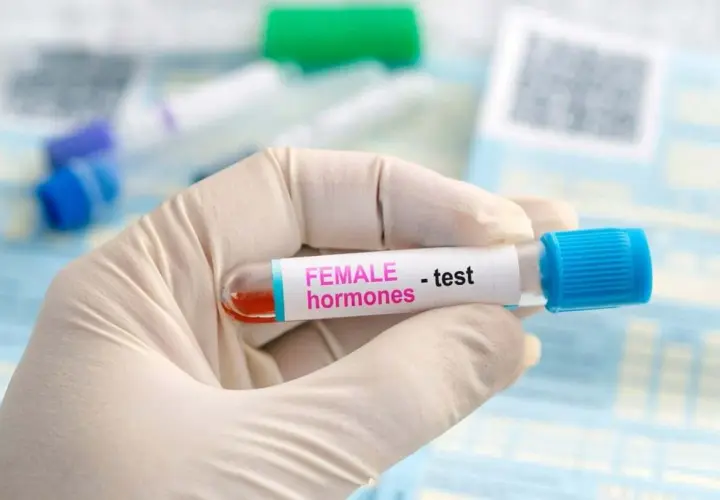 Rękawiczka medyczna trzyma probówkę z krwią do badania poziomu hormonów, w tym FSH.