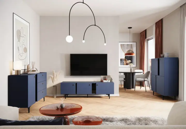 Nowoczesny salon z granatowymi meblami i ekstrawagancką lampą. W tle stół z krzesłami.