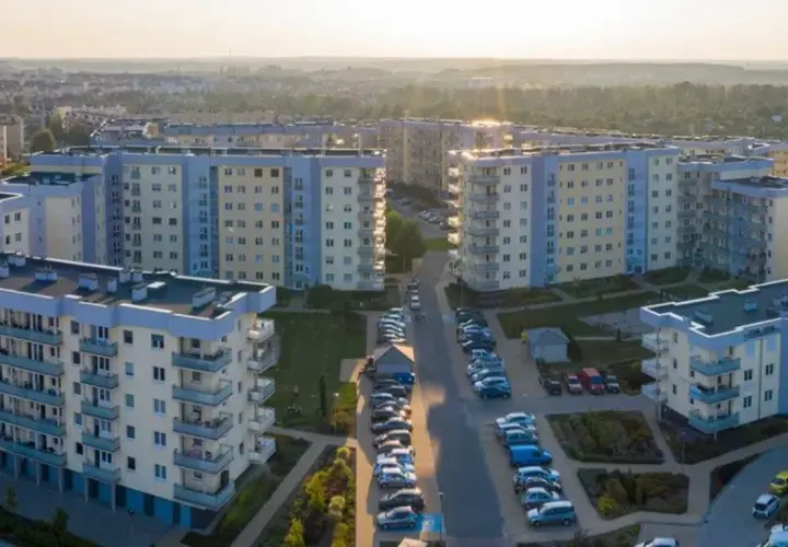 Widok z lotu ptaka na osiedle bloków mieszkalnych z balkonami i parkingami.