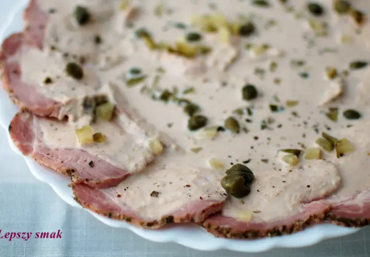 Cienkie plastry pieczonego mięsa wieprzowego polane kremowym sosem z kaparami i ziołami, klasyczne vitello tonnato.