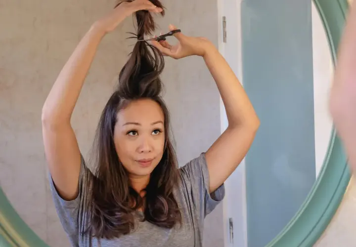Mujer se corta el pelo en casa, creando un corte de pelo a capas.