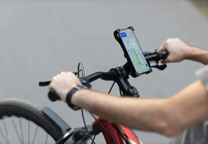 Rowerzysta z telefonem na kierownicy, nawigacja pokazuje trasę. Idealne do śledzenia treningów z Endomondo.
