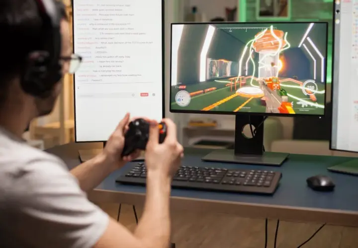 Gracz z kontrolerem w rękach gra w grę na komputerze, szukając inspiracji na nazwy do Fortnite w czacie.