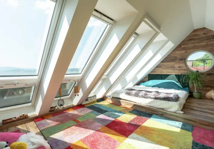 Un letto accogliente in una soffitta luminosa, con un tappeto colorato che dona un significato di gioia e calore.