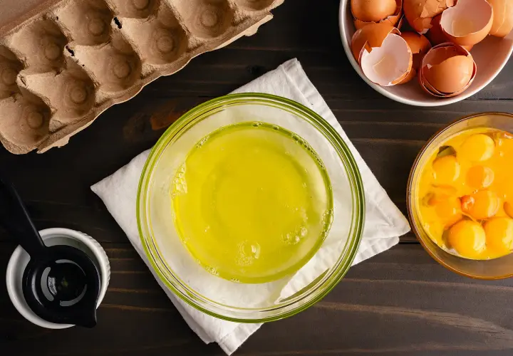 Préparation pour une recette : blancs d'œufs dans un bol, jaunes d'œufs dans un autre, et coquilles dans une coupelle. Le tout prêt à être mis au frigo.