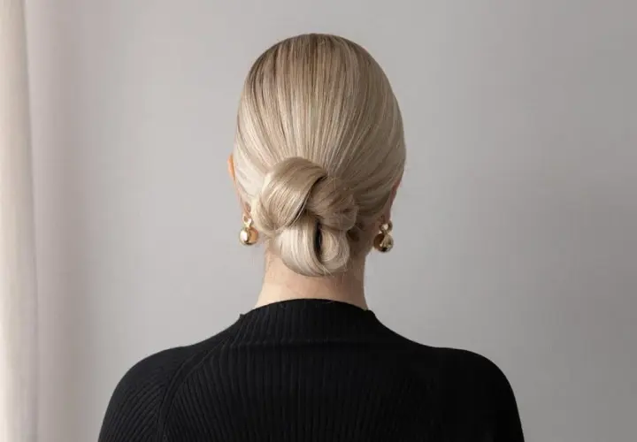 Elegancki kok z blond włosów, idealny na proste fryzury ślubne. Złote kolczyki dodają blasku.