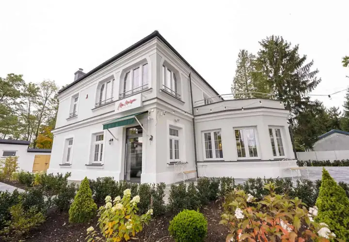 Elegancka willa z napisem "La Maison" Michel Moran. Piękny ogród przed budynkiem.