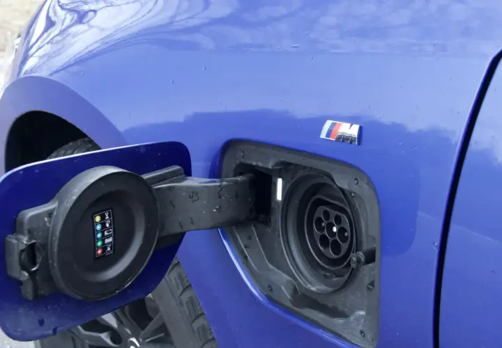 Niebieskie BMW 330e z otwartą klapką gniazda ładowania. Widoczny symbol M.