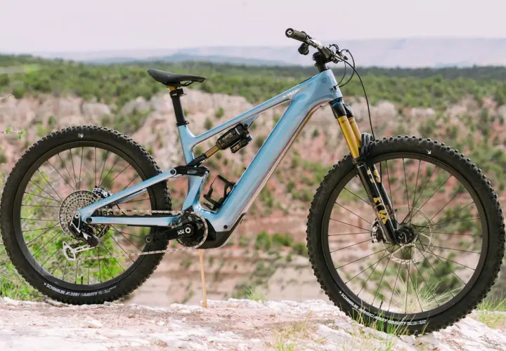 A light blue specialized levo 4 electric mountain bike is parked on a rocky trail with a scenic canyon in the background.