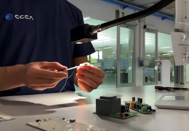 Técnico ensambla componentes electrónicos bajo una luz focalizada, asegurando cada lumen unidad.