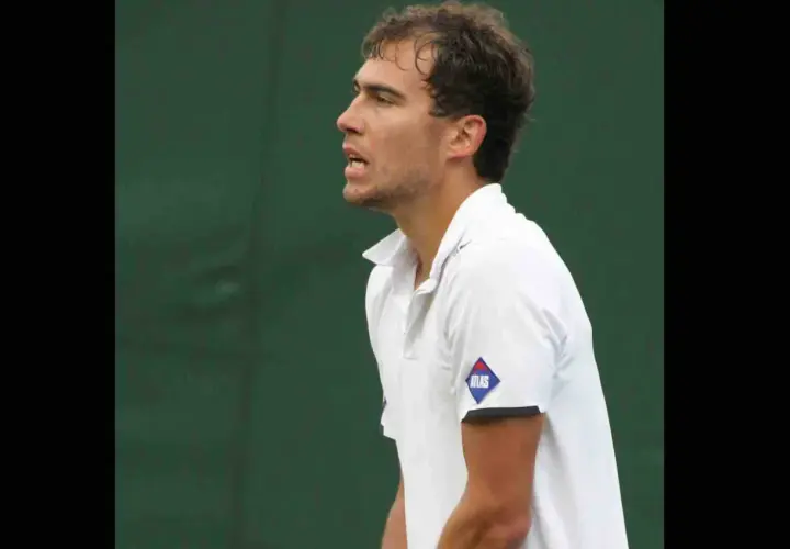 Jerzy Janowicz, z rakietą w dłoni, unosi palec wskazujący, świętując zwycięstwo. Jego majątek rośnie z każdym wygranym meczem.