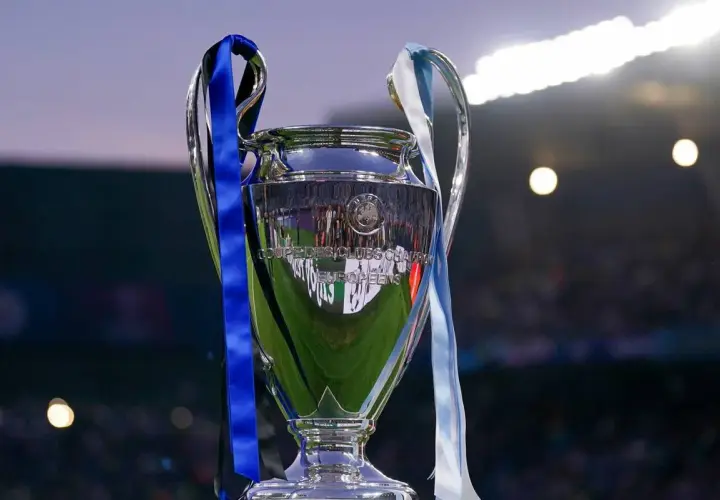 Trofeum Ligi Mistrzów, symbol marzeń i celów w piłkarskich rankingach. Błyszczący puchar z niebieskimi i jasnymi wstążkami, odbijający światła stadionu.