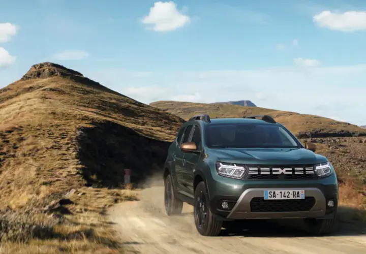 Zielony Dacia Duster off road pokonuje piaszczystą drogę wśród skalistych wzgórz.