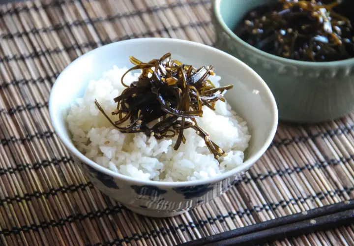 A bowl of white rice topped with dark, glistening tsukudani, a savory seaweed dish. This image hints at a delicious tsukudani recipe.