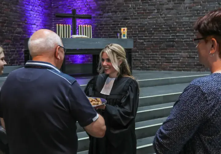 Frauen in der kirche: Eine Geistliche teilt Brot mit Gemeindemitgliedern.