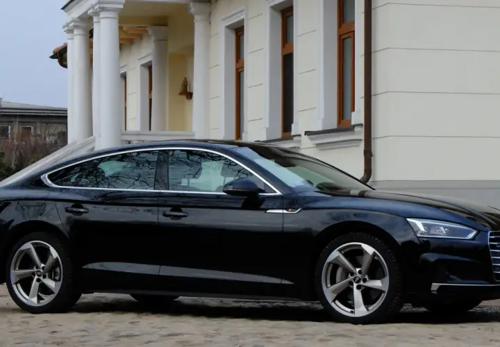 Eleganckie, czarne Audi A5 z 2018 roku zaparkowane przed klasycznym budynkiem z kolumnami.