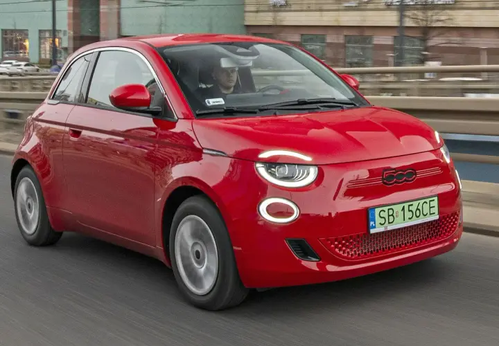Czerwony Fiat 500 jedzie po drodze. Sprawdź aktualną fiat 500 cena i dowiedz się więcej o tym stylowym samochodzie.