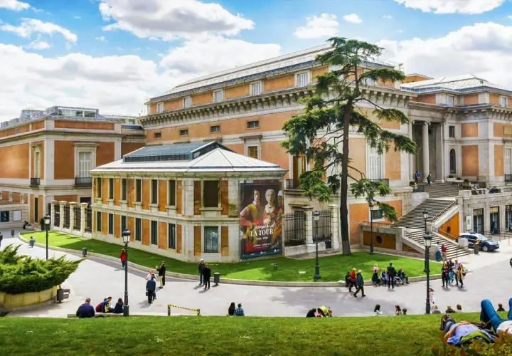 Muzeum Prado w Madrycie z ludźmi odpoczywającymi na trawie i zwiedzającymi.