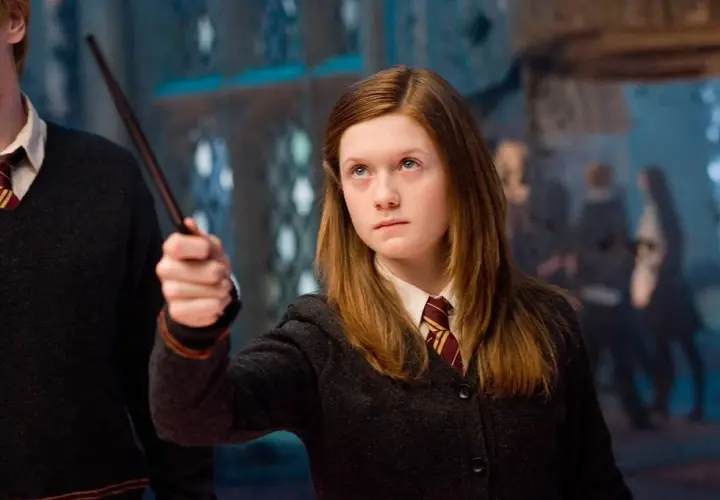 Bonnie Wright jako Ginny Weasley w filmach o Harrym Potterze, z różdżką w dłoni, gotowa do rzucenia zaklęcia.