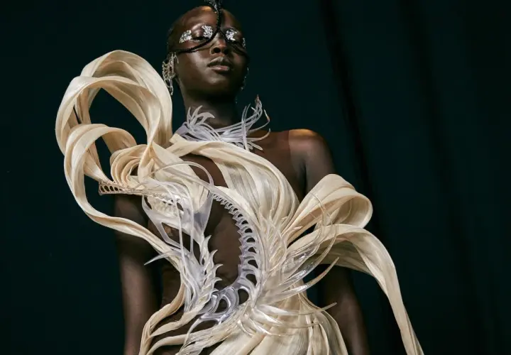Mannequin portant une création avant-gardiste, un vêtement d'impression 3D aux formes organiques et futuristes, orné de détails argentés sur le visage.