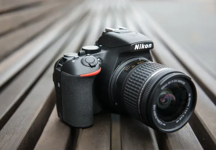 Czarny aparat Nikon D3300 z obiektywem na drewnianym tle.