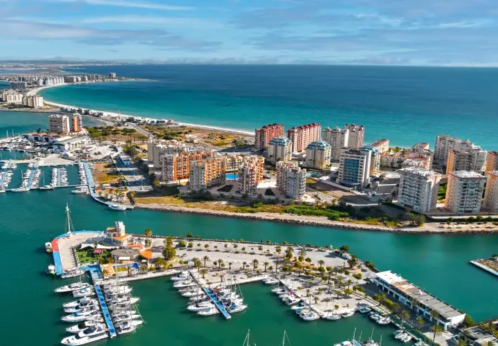 Widok na La Manga, Hiszpania: luksusowe apartamenty i pełen jachtów port nad turkusowym morzem.