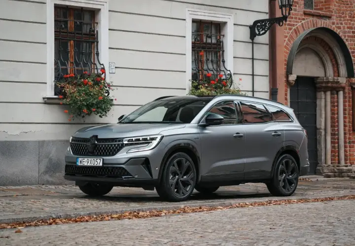 Nowy Renault Espace 2024 w szarym kolorze na brukowanej uliczce, z kwiatami w oknach.