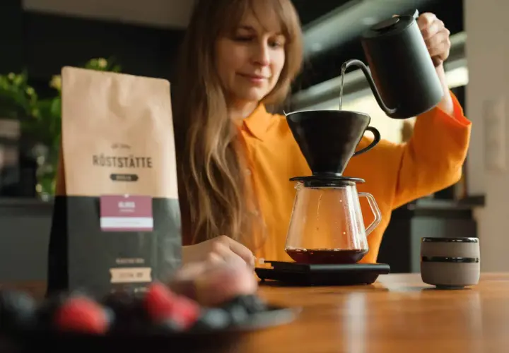 Frau brüht Kaffee. Informationen über Kaffee in der Schwangerschaft folgen.