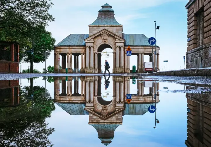 Odbicie zabytkowej budowli w kałuży po deszczu. Spacer po Szczecinie, odkrywając jego atrakcje dla dorosłych, to świetny pomysł na weekend.