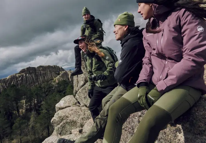Grupa przyjaciół w górach, ubrana w kurtki hardshell i softshell, cieszy się widokiem.