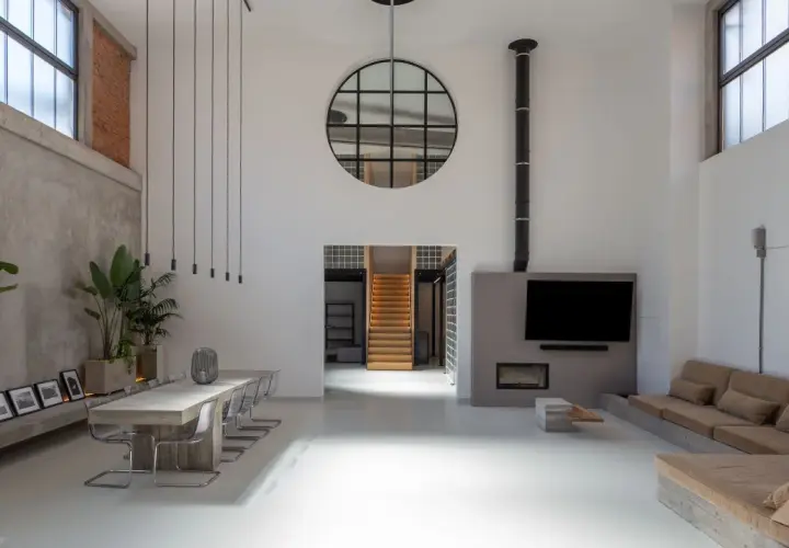 Großzügiges Loft mit Betonwänden, Stahlfenstern und einer Treppe. Der Stil ist **industrial chic**, mit Pflanzen und einer gemütlichen Sitzecke.
