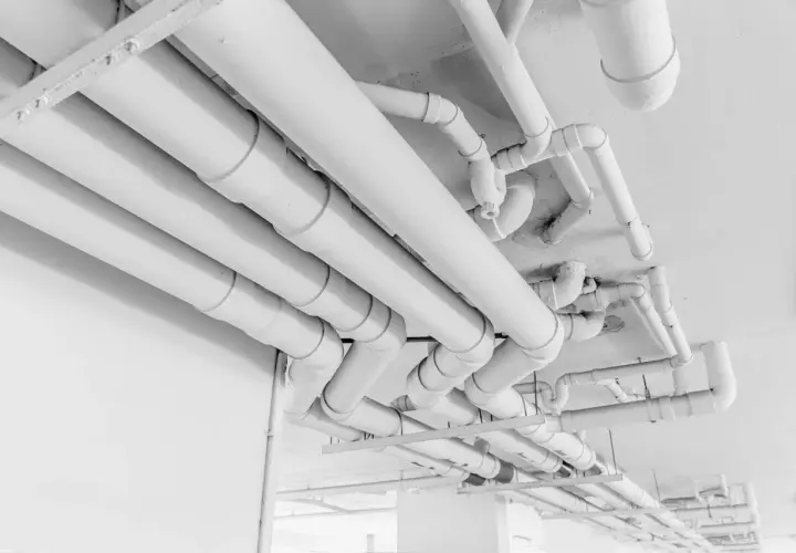 Skomplikowany system białych rur pehd biegnie pod sufitem, tworząc labirynt instalacji.