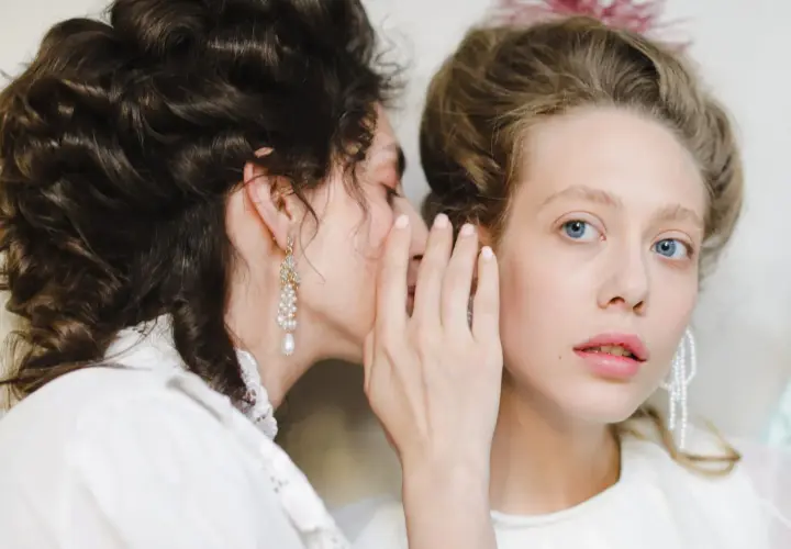 Szeptane plotki, które mogą prowadzić do zniesławienia, rozchodzą się między dwiema kobietami w stylizacjach retro.